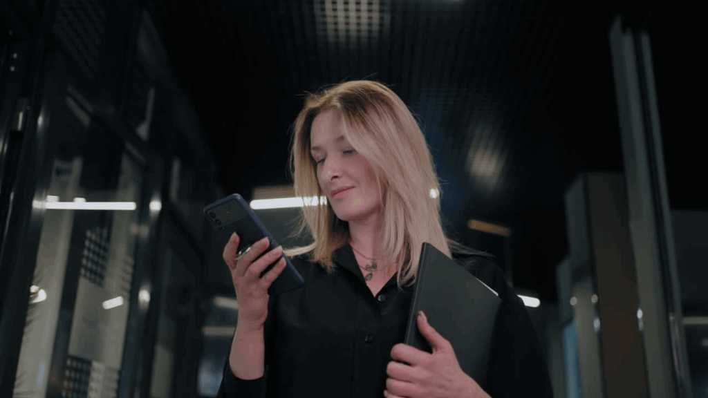 Professional businesswoman in black checking mobile business communications in modern office setting